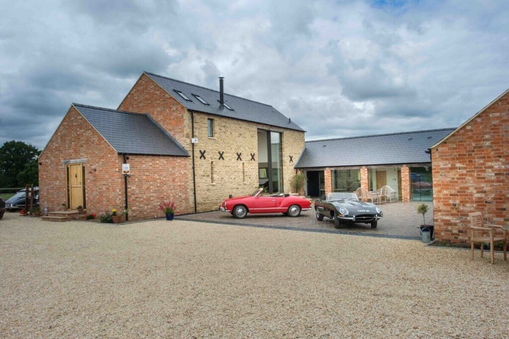 Barn conversion planning. Converted barn with red sports car parked outside